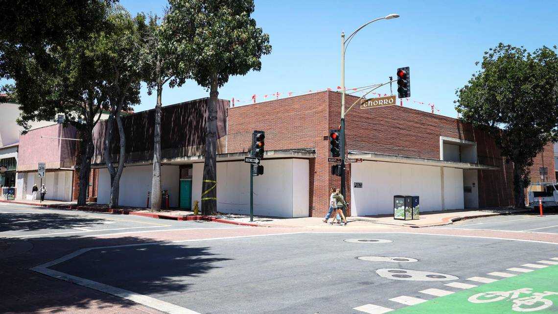 Street corner view of a vacant brick building with white-covered windows and construction barriers along Chorro Street in downtown San Luis Obispo, California.