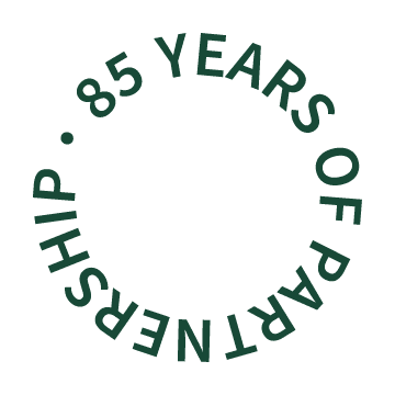 Green circular text logo reading 85 years of partnership