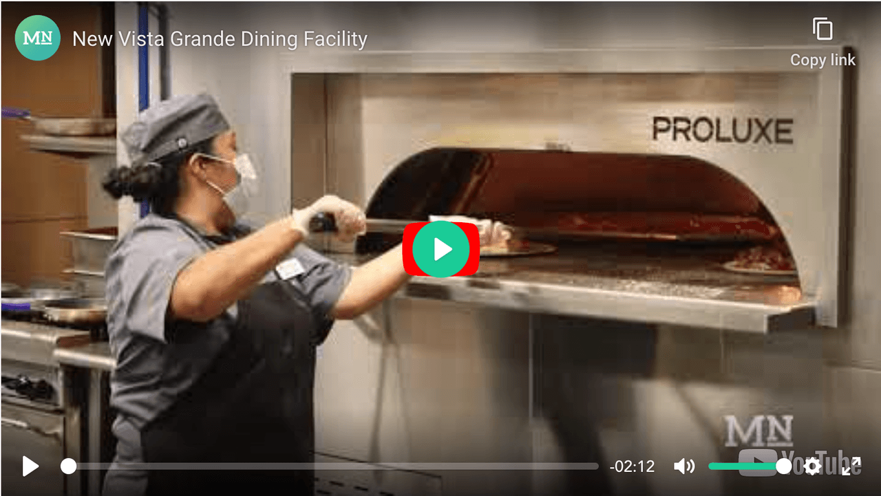 An employee putting a pizza in the oven
