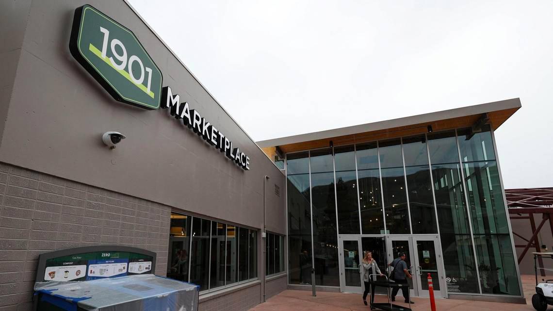 Exterior of the 1901 Marketplace building at Cal Poly, featuring modern glass architecture and the 1901 logo above the entrance as students walk inside.