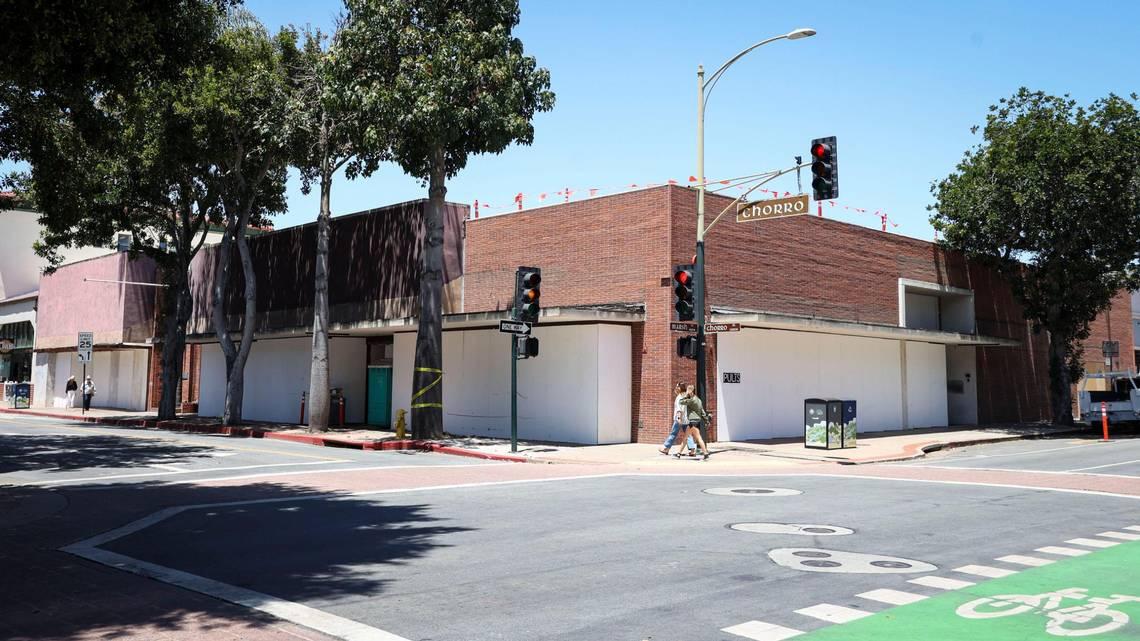 Street corner view of a vacant brick building with white-covered windows and construction barriers along Chorro Street in downtown San Luis Obispo, California.
