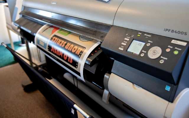 A large-format printer produces a colorful poster at Cal Poly Print and Copy Services.